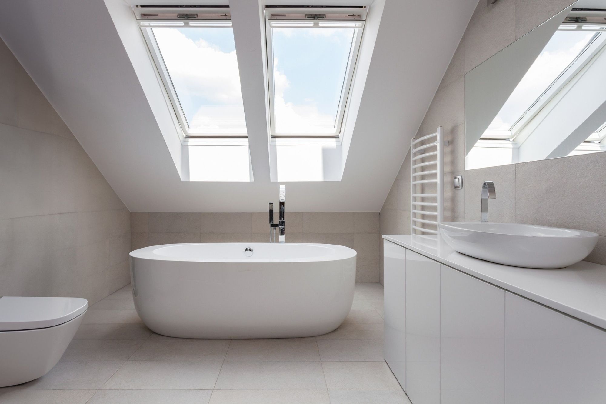 Modernes Badezimmer mit freistehender Badewanne, elegantem Waschtisch und Oberlichtern, die das minimalistische Design beleuchten.
