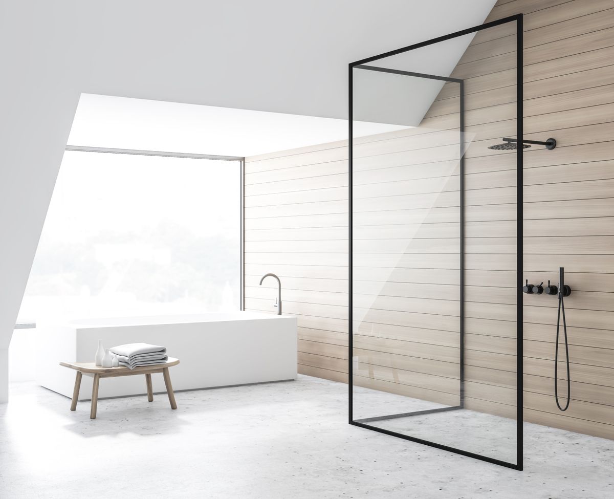 Ein modernes Badezimmer mit Glasdusche, freistehender Badewanne und Holzvertäfelung, das durch ein großes Fenster mit natürlichem Licht erhellt wird.
